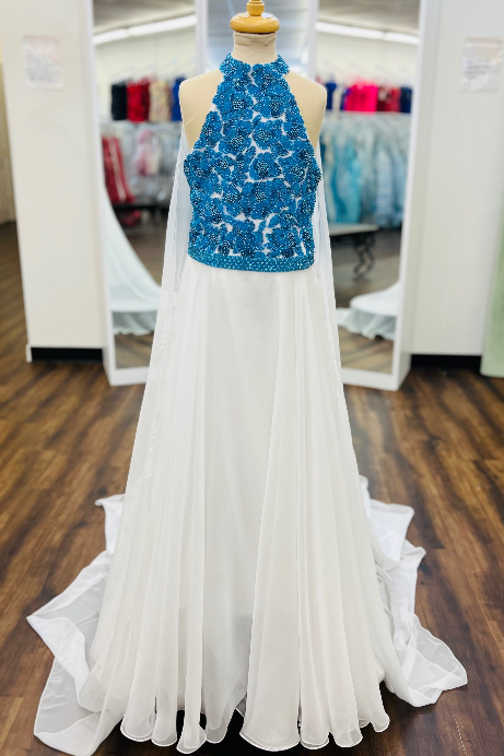 A formal gown displayed on a dress form inside a boutique. The dress has a high halter neckline with a bright blue beaded bodice and a flowing white chiffon skirt with a long train.