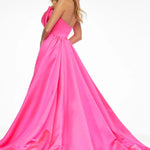 A woman modeling a bright hot pink one-shoulder ball gown with a voluminous skirt and train, photographed against a clean white studio background.