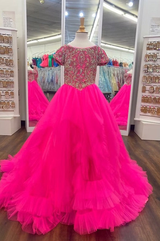 A bright hot pink ball gown with a heavily beaded and sequined pink and gold bodice, displayed on a mannequin in a clothing store.