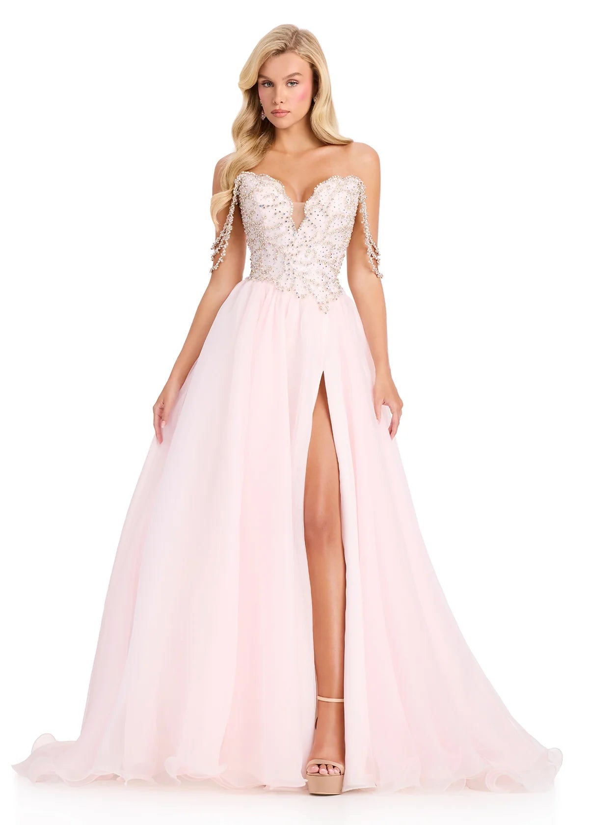 Woman wearing a pink evening gown with a high slit on a white background
