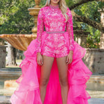 Woman wearing a bright pink sequin outfit with a ruffled skirt in front of a fountain.