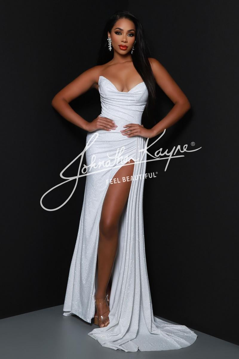 A woman modeling a floor-length white strapless gown with a sweetheart neckline, ruched bodice, high thigh slit, and a slight train against a dark studio background. A large white script watermark reading 'Jennifer Kayne' is overlaid across the center.