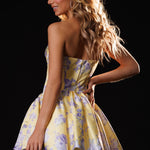 Woman wearing a yellow floral dress with 'Rachel Allan' branding on a black background