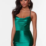 A woman modeling a shiny emerald green satin mini dress with spaghetti straps against a plain white studio background.