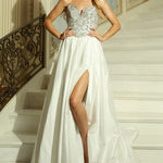 Woman in a luxurious white and silver ballgown with heavy sequins and beading  standing on a staircase.