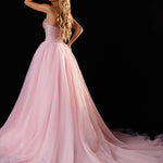 A woman modeling a pale pink strapless ball gown with a full tulle skirt and long train against a black studio background. The brand name 'RACHEL ALLAN' appears in the top right corner.