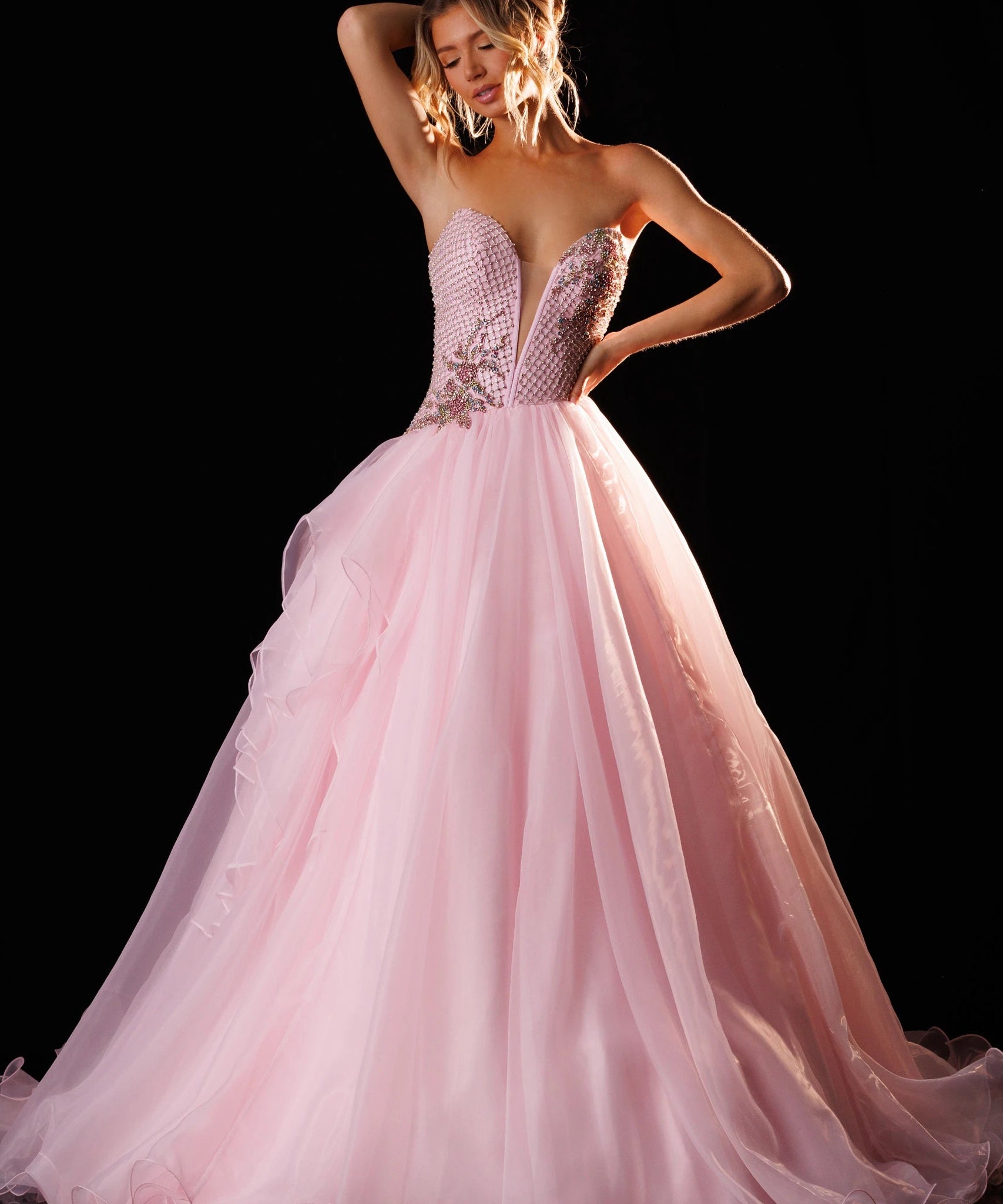 A woman models a pink ball gown with a strapless sweetheart bodice, beaded embellishments, and a voluminous layered tulle skirt against a black studio background. The brand name 'RACHEL ALLAN' is printed in the top right corner.