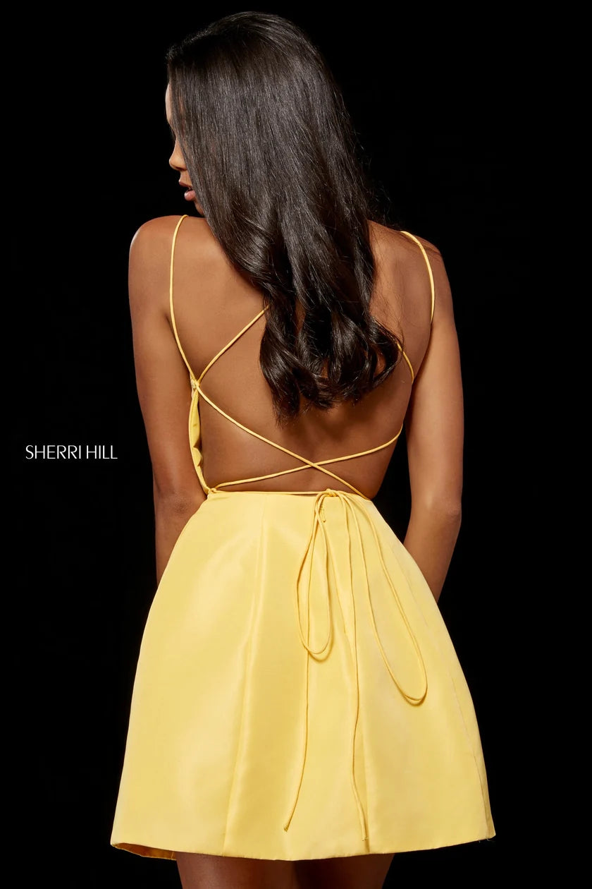A woman shown from the back wearing a bright yellow spaghetti-strap dress with an open back and tie detail, photographed against a solid black background. The Sherri Hill brand name is visible on the left side.