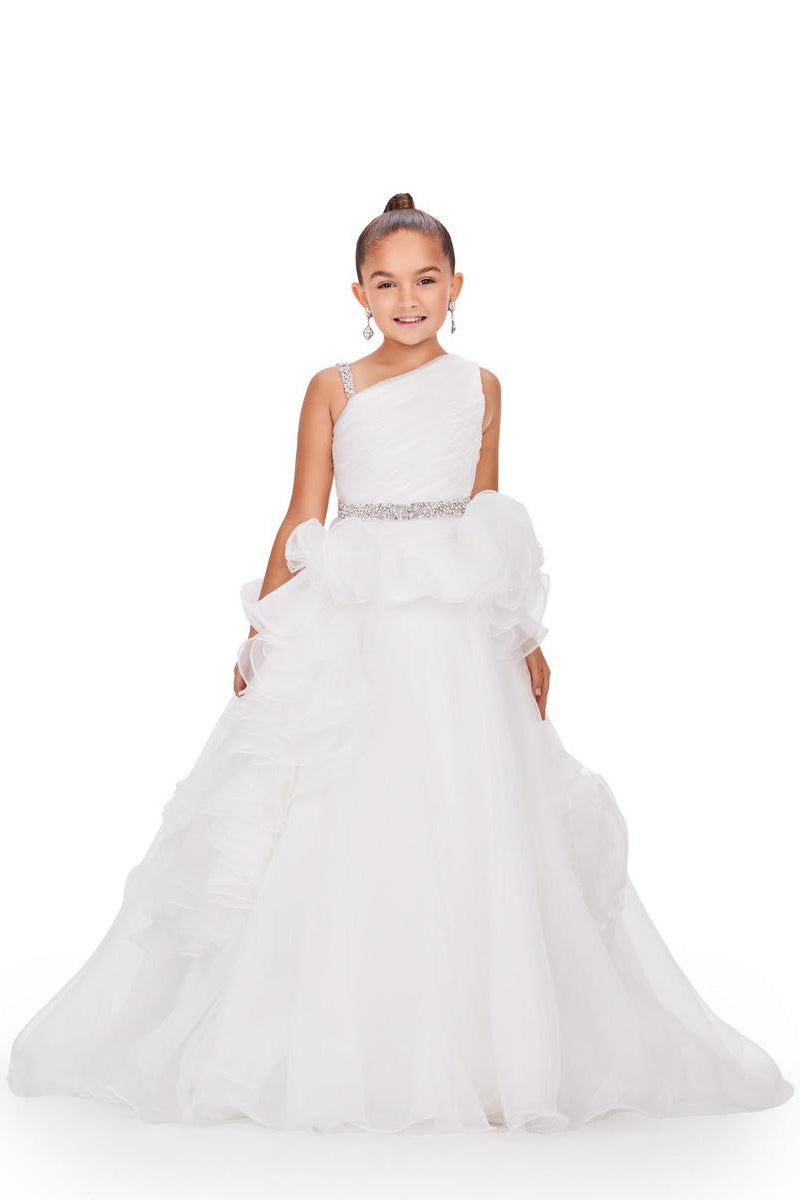A young girl modeling a white one-shoulder ball gown with a ruffled tulle skirt and a sparkling silver embellished waistband, set against a plain white background.