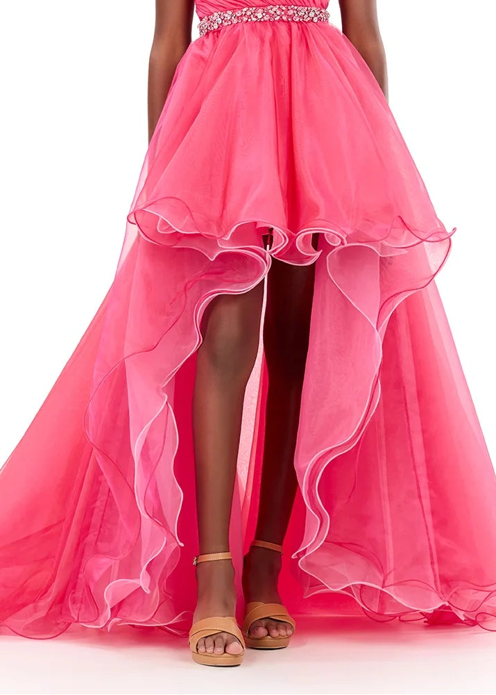 Young girl wearing a pink formal gown with a flower detail on a white background