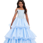 Young girl wearing a light blue formal gown with ruffled layers on a white background