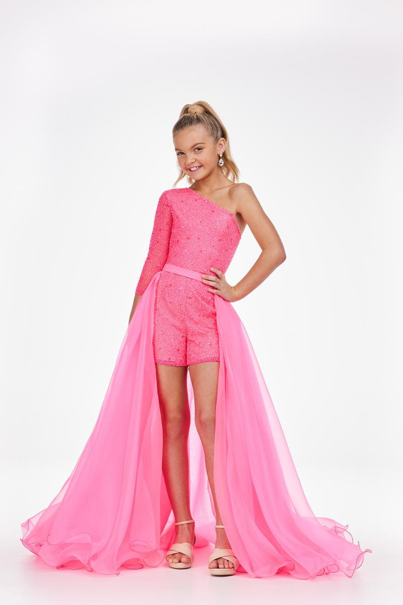 Young girl is modeling a pink organza overskirt atop a pink romper on a white background.