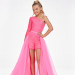 Young girl is modeling a pink organza overskirt atop a pink romper on a white background.