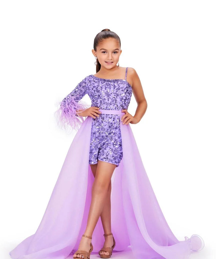 Young girl models a light purple organza overskirt over a sequin romper in front of a white background.