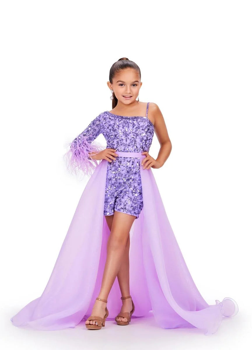 Young girl models a light purple organza overskirt over a sequin romper in front of a white background.