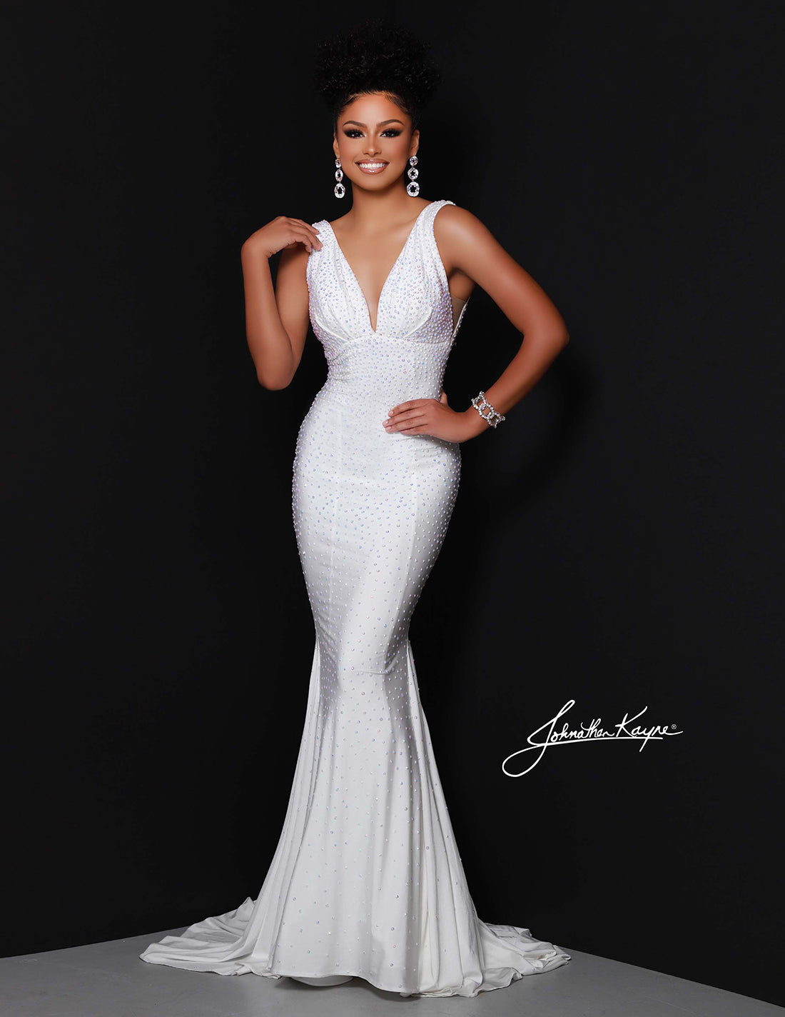 Woman in a white evening gown posing against a black background