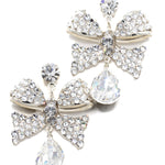 Pair of decorative earrings with bow and teardrop designs on a white background