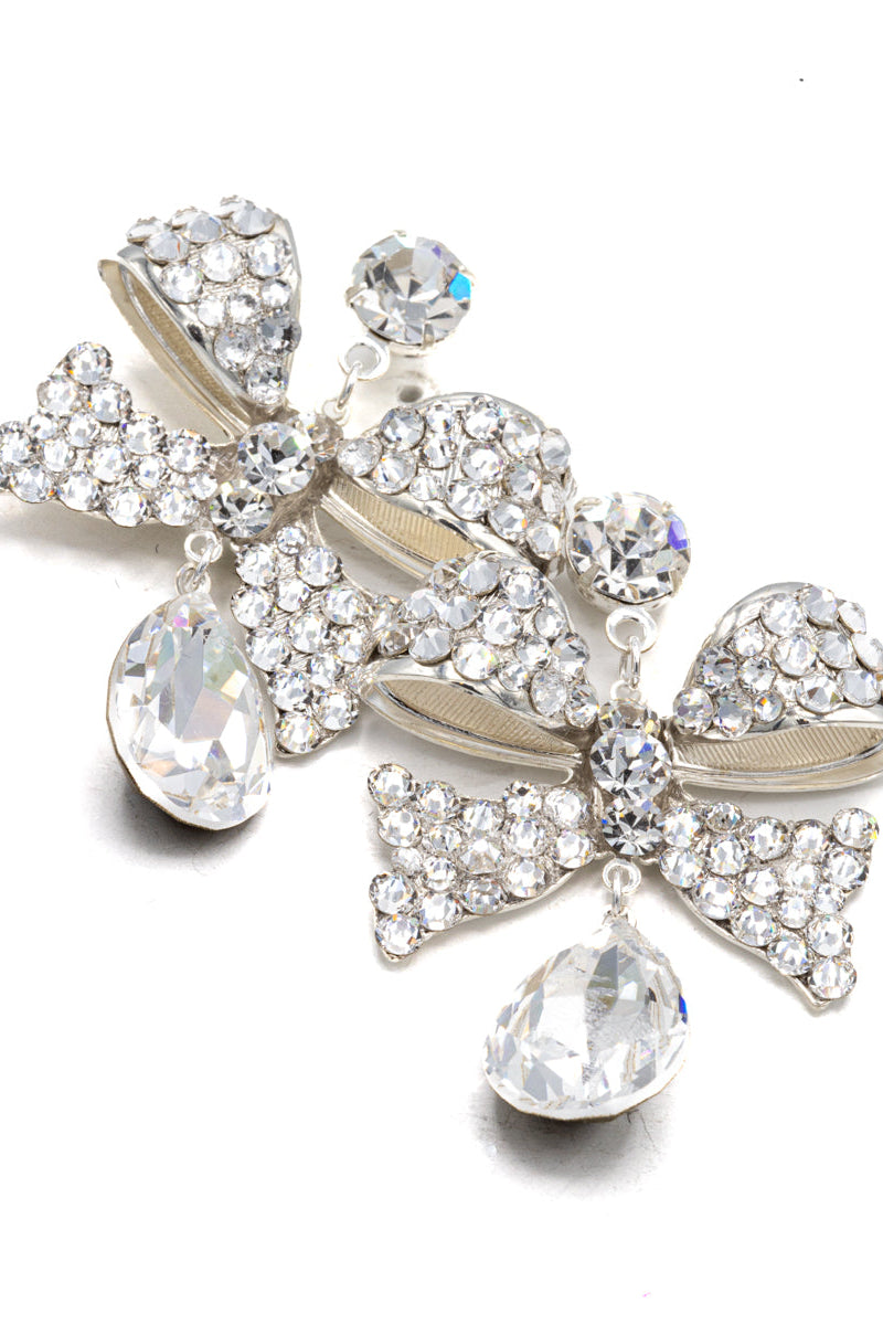 Pair of decorative earrings with bow and teardrop designs on a white background