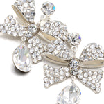 Pair of decorative earrings with bow and teardrop designs on a white background