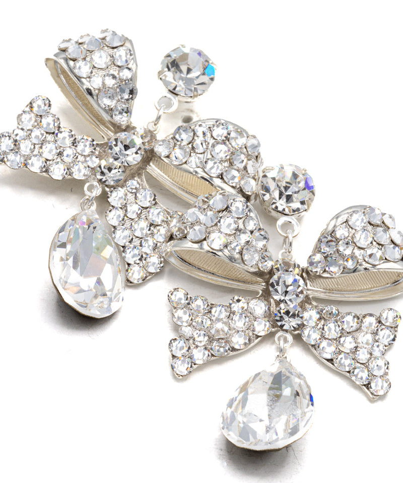 Pair of decorative earrings with bow and teardrop designs on a white background