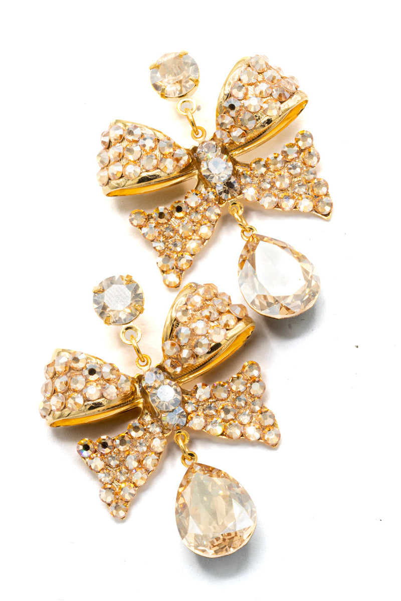 Gold bow-shaped earrings with crystal accents on a white background