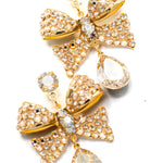 Gold bow-shaped earrings with crystal accents on a white background