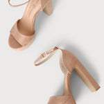 A pair of women's platform high-heel sandals in a light nude pink suede-like material, featuring open toes, ankle straps with gold-tone buckles, and chunky block heels, shown on a light gray background.