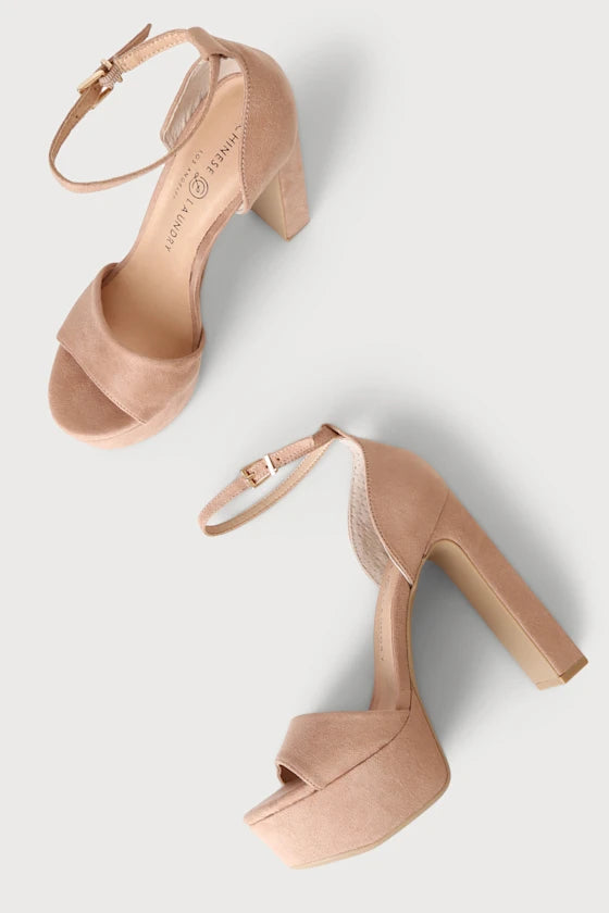 A pair of women's platform high-heel sandals in a light nude pink suede-like material, featuring open toes, ankle straps with gold-tone buckles, and chunky block heels, shown on a light gray background.
