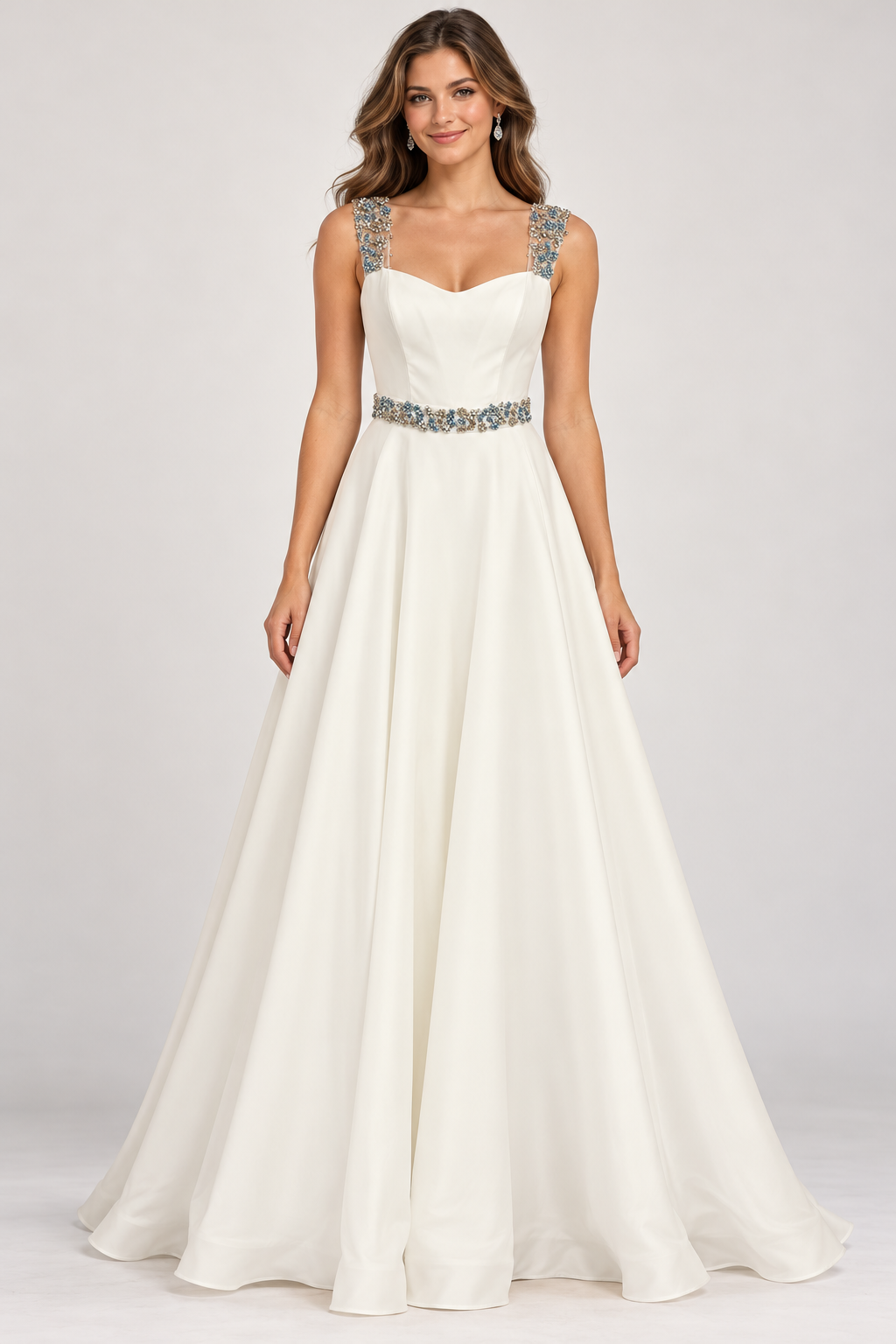 A woman modeling a floor-length A-line wedding dress in ivory with silver beaded embellishments on the straps and waist.