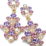A pair of gold-tone statement dangle earrings adorned with faceted crystal rhinestones in shades of purple, pink, and clear, arranged on a clean white background.