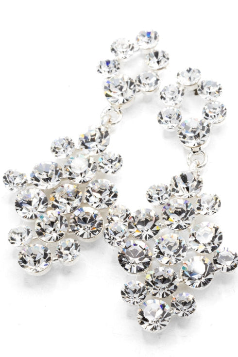A pair of silver-tone dangle earrings adorned with clear faceted rhinestones, arranged in a cascading floral cluster design on a white background.