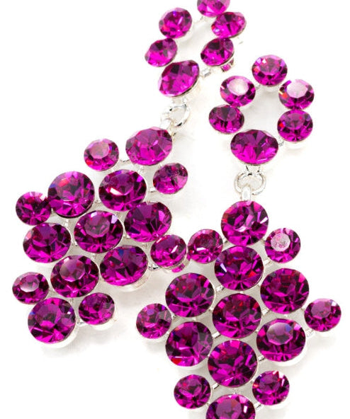 A pair of silver-tone statement earrings adorned with multiple round, faceted fuchsia crystals, set against a plain white background.