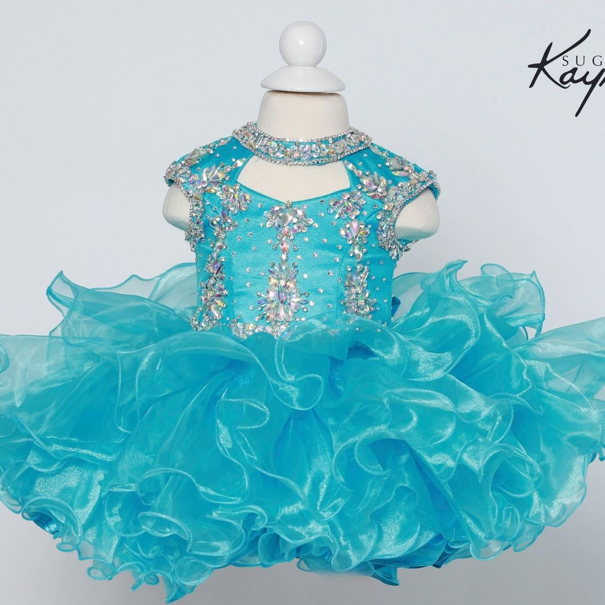 Turquoise dress with sparkling embellishments on a mannequin against a light gray background.